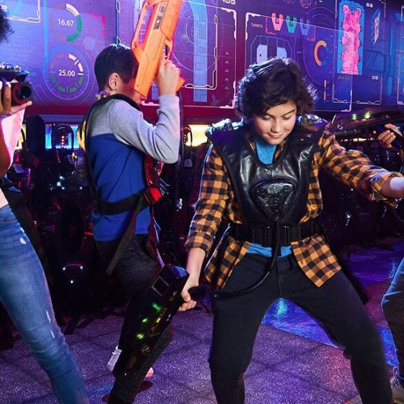 Niños jugando laser tag en Main Event Pharr con chalecos y luces LED