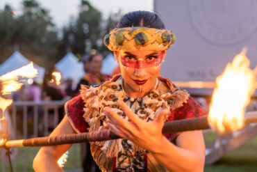 Mujer mirando fijamente a la cámara con una vara de fuego en ropa tradicional