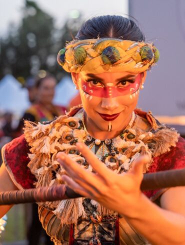 Mujer mirando fijamente a la cámara con una vara de fuego en ropa tradicional
