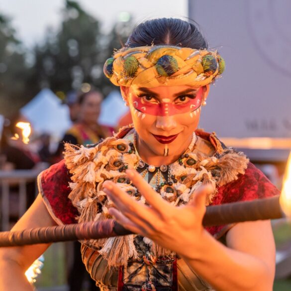Mujer mirando fijamente a la cámara con una vara de fuego en ropa tradicional