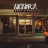 Exterior de Monarca Baja Kitchen iluminado durante la noche en Brownsville