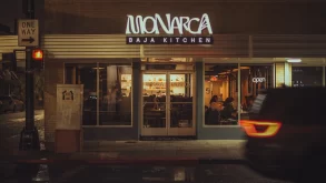Exterior de Monarca Baja Kitchen iluminado durante la noche en Brownsville