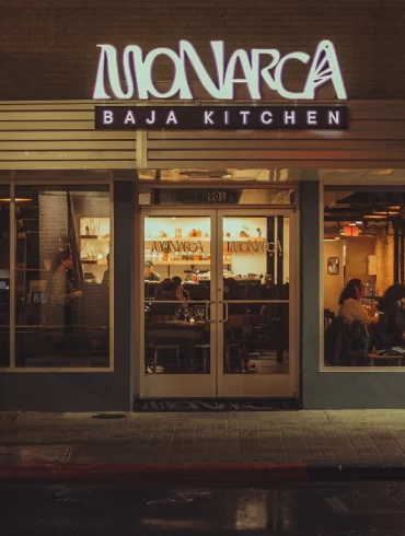 Exterior de Monarca Baja Kitchen iluminado durante la noche en Brownsville