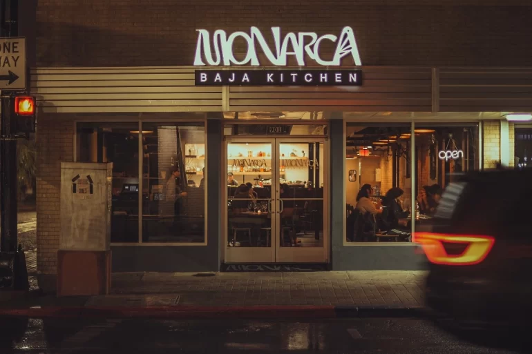 Exterior de Monarca Baja Kitchen iluminado durante la noche en Brownsville