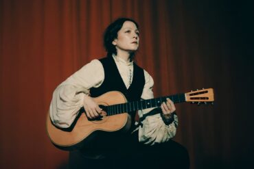 Natalia Lafourcade tocando su guitarra acústica en un escenario promocional Cancionera Tour 2025