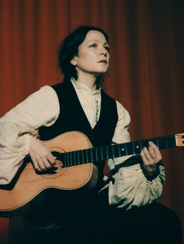 Natalia Lafourcade tocando su guitarra acústica en un escenario promocional Cancionera Tour 2025