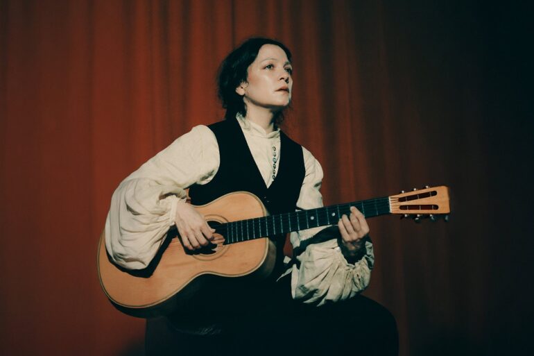 Natalia Lafourcade tocando su guitarra acústica en un escenario promocional Cancionera Tour 2025