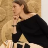 Mujer sentada con falda artística y bolso de piel en boutique de Purificación García McAllen