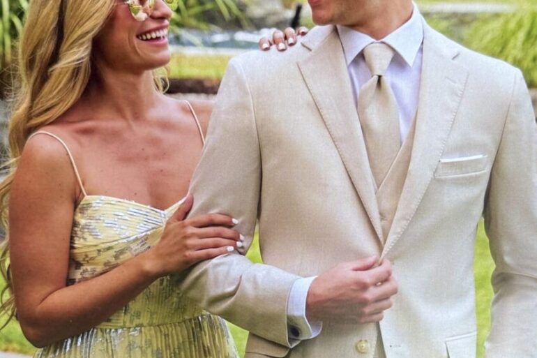 Hombre con traje de prom blanco y lentes de sol junto a mujer, listos para su evento