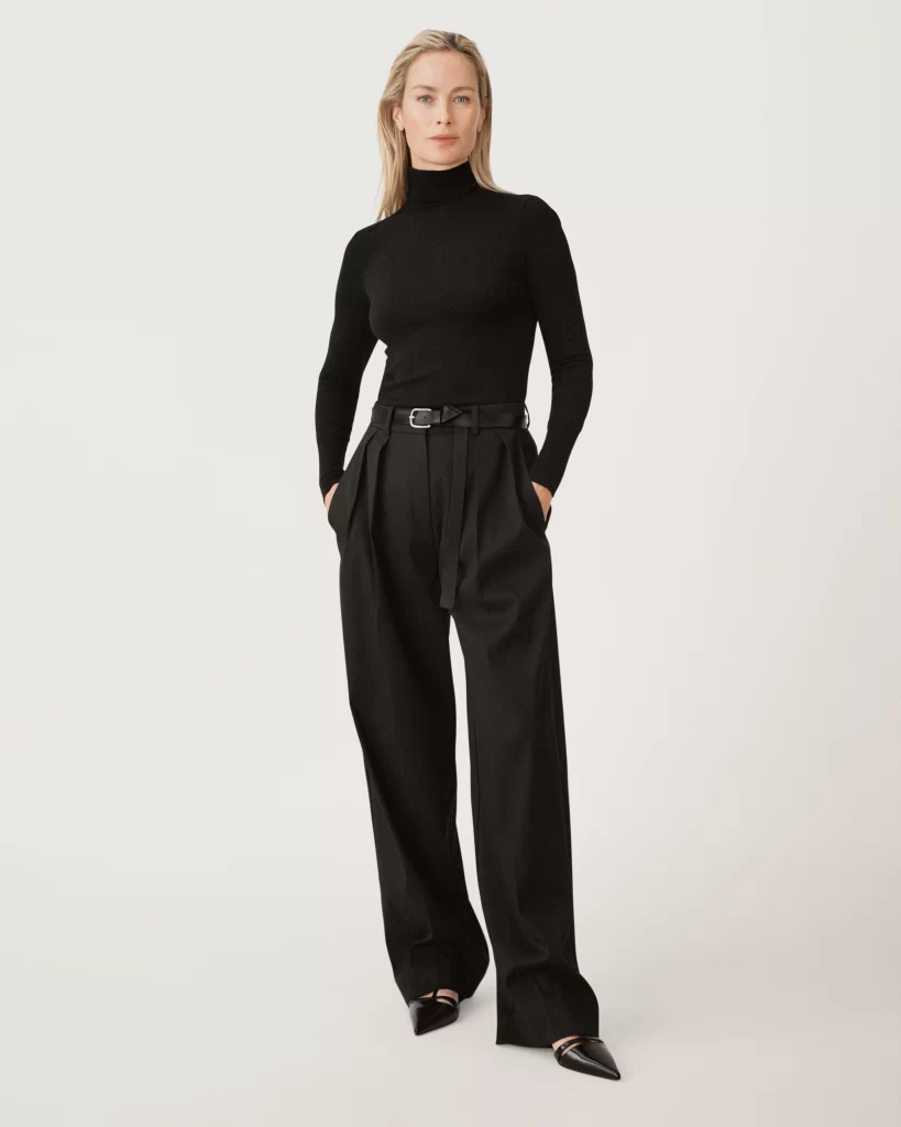 Modelo usando suéter de cuello alto y pantalón de vestir negros de la colección Zara 50 años.