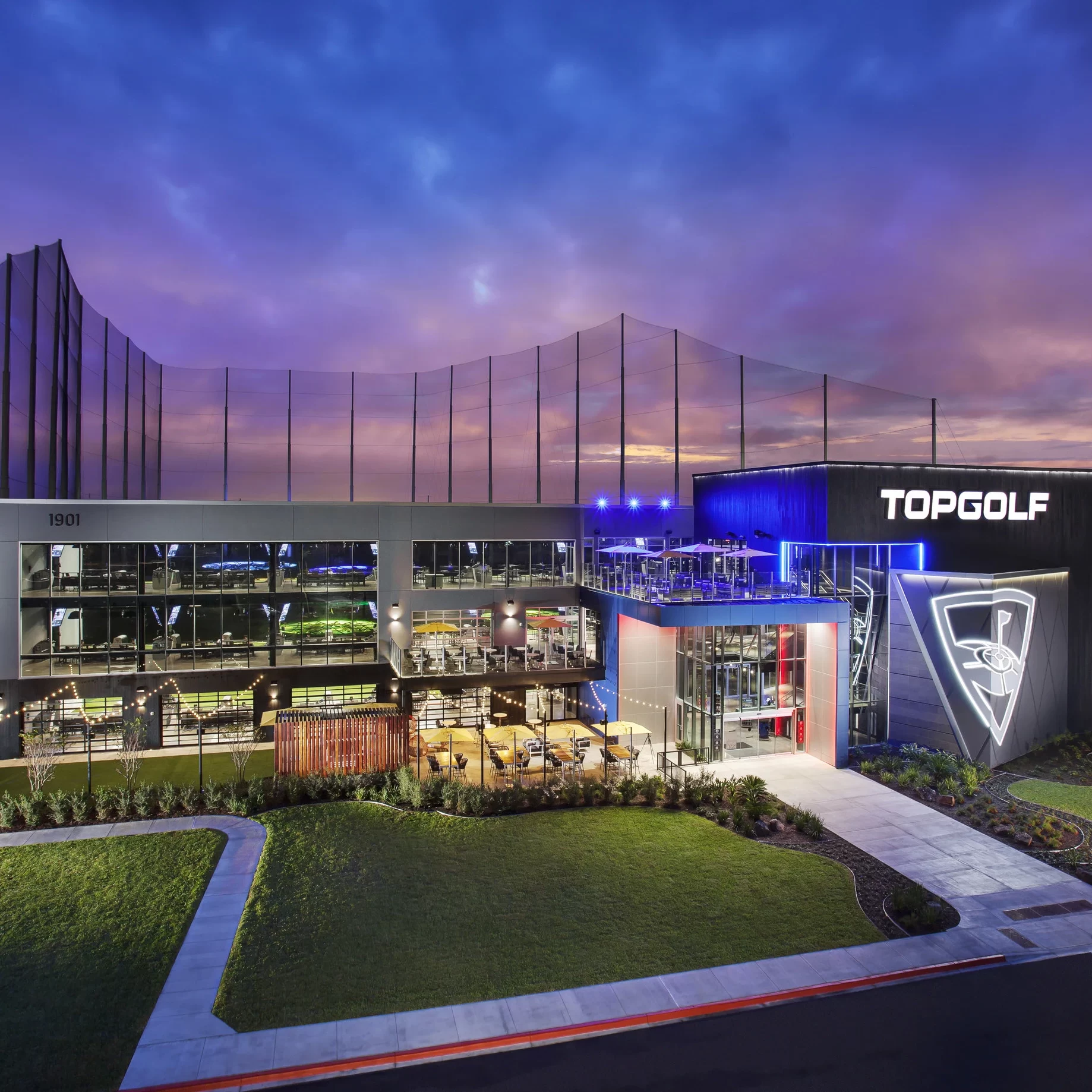 Vista exterior de Topgolf Pharr al atardecer con iluminación nocturna
