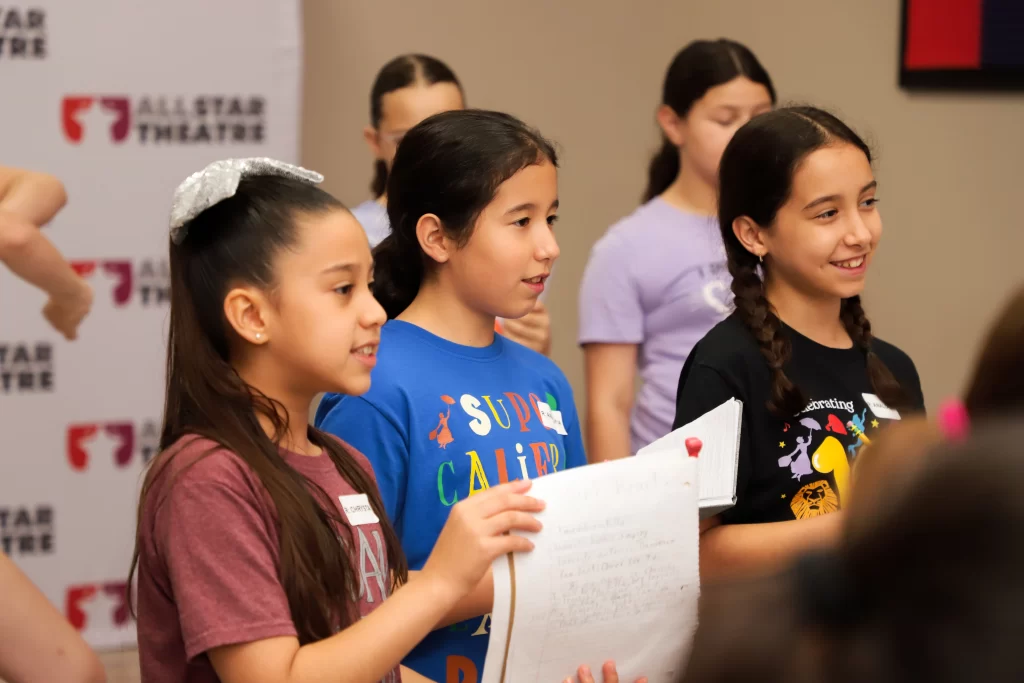 Niñas cantando y leyendo guiones en campamento de teatro